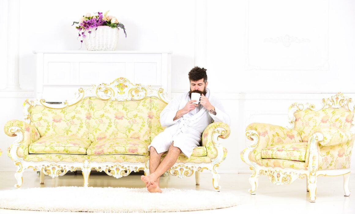 Bearded man drinking coffee on sofa